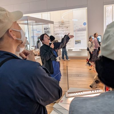参加者に博物館の展示を説明する女性