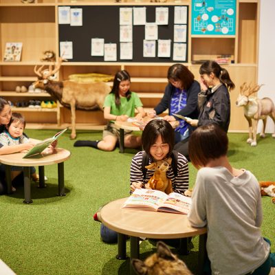 テーブルで絵本を読む女性と子ども
