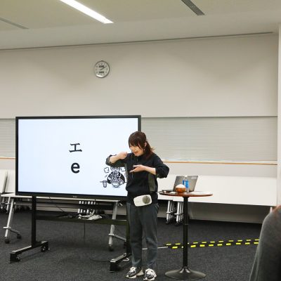 モニターの前で参加者に説明をする女性