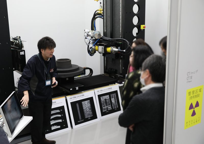 博物館の分析機械を説明する博物館職員