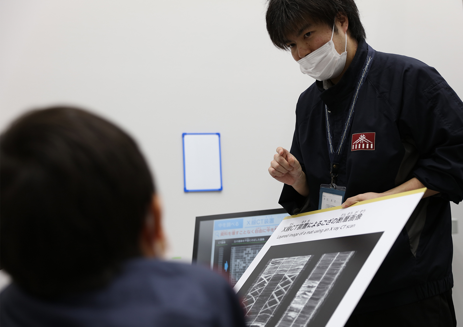 博物館の分析画像を説明する博物館職員