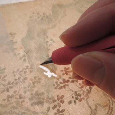 ナイフで絵画を修復する手元