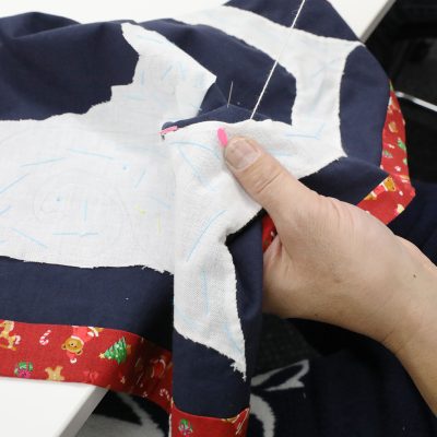 白・紺・赤の布に刺繍を行う手元